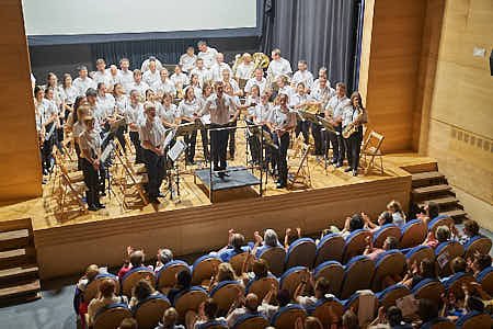 Banda de música tocando dentro de un teatro con baja iluminación