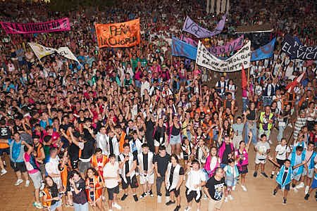 Gente celebrando un pregón de fiestas en una plaza mayor
