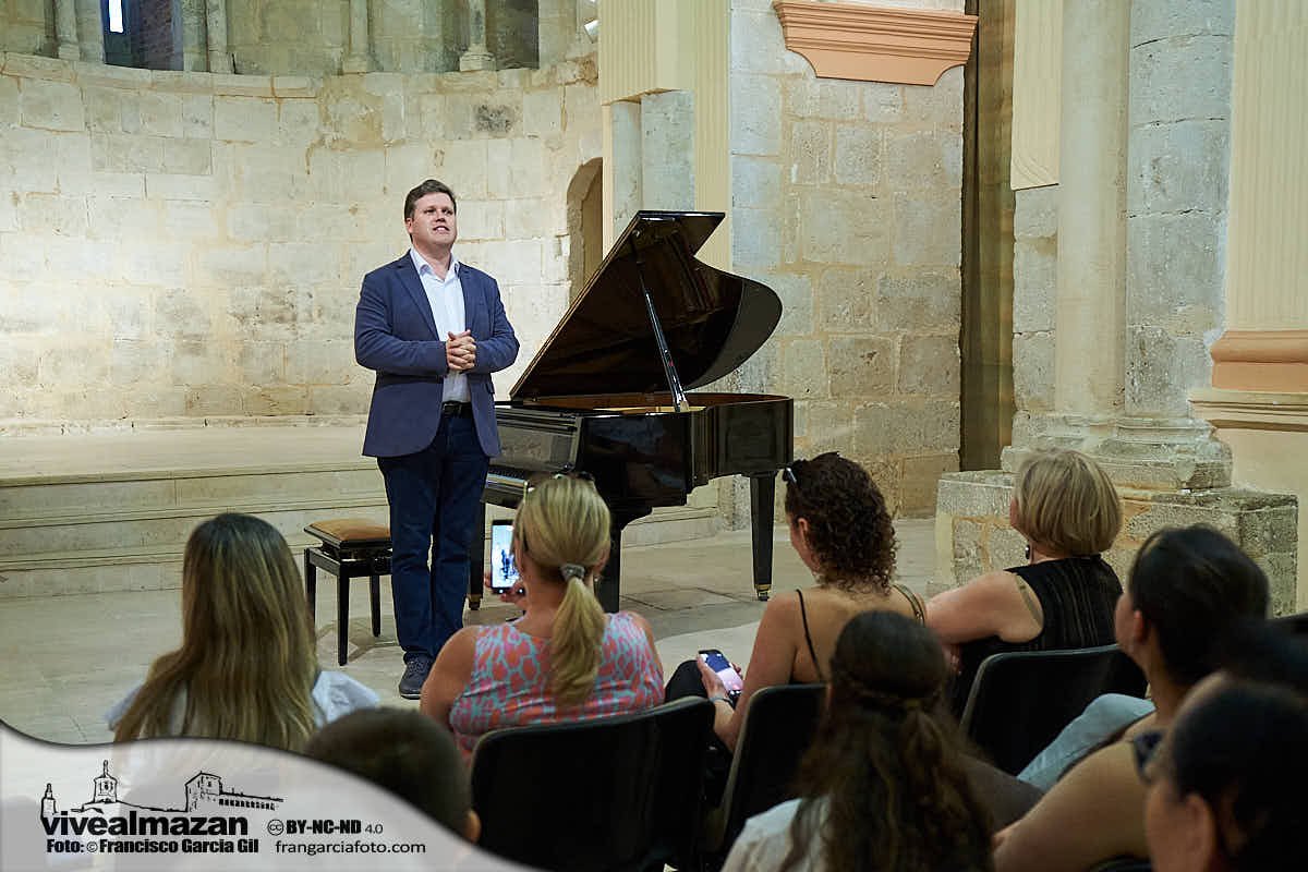 musico al lado de su piano hablando al público asistente