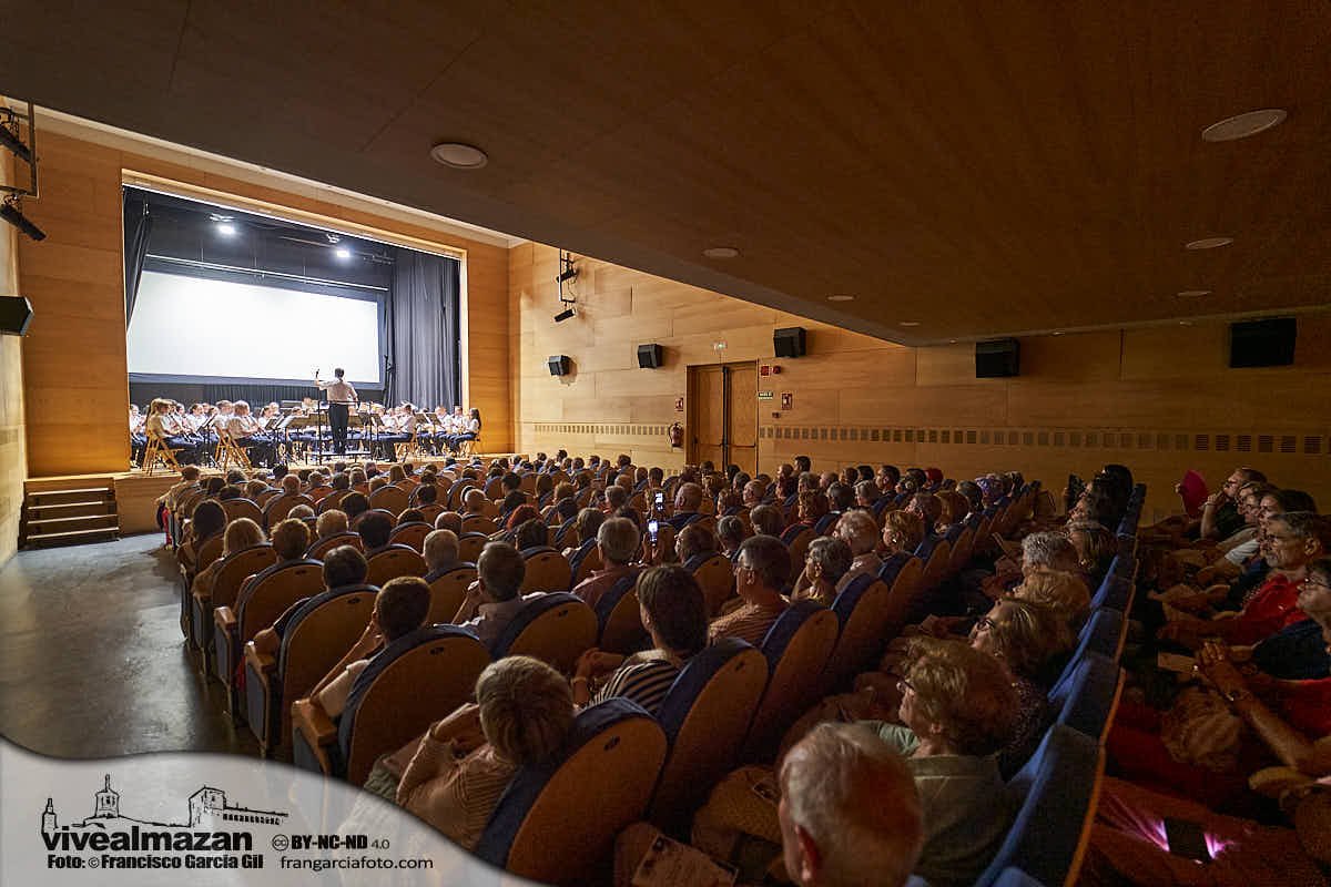 Banda de música tocando dentro de un teatro con baja iluminación